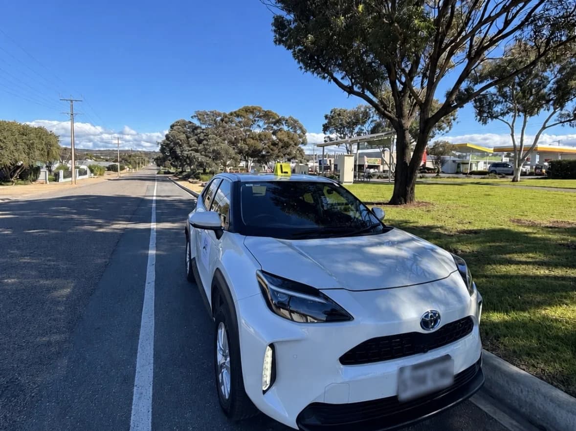 The Adelaide Hills Driving School dual-control Toyota Yaris Cross with L plates, parked on a wide arterial road in Murray Bridge
