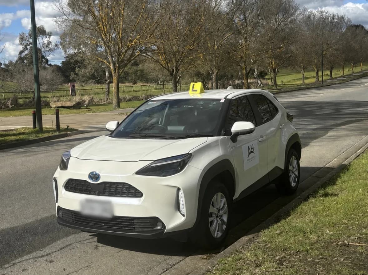 The Adelaide Hills Driving School dual-control Toyota Yaris Cross with L plates, parked on a quiet kerbside road in Mount Barker